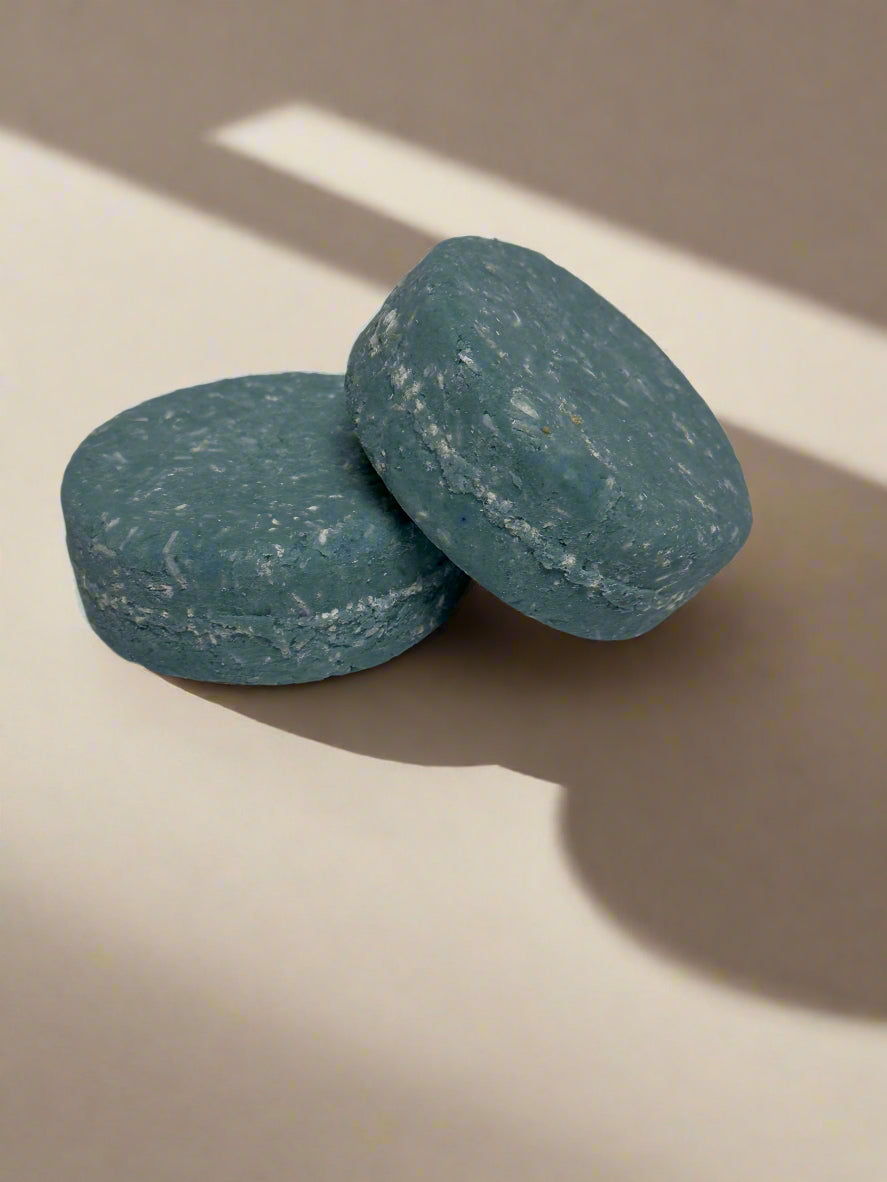 2 blue shampoo bars stacked, neutral background with shadows.