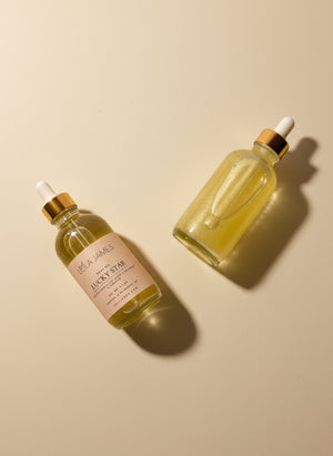 Two glass bottles with gold caps on a light beige background