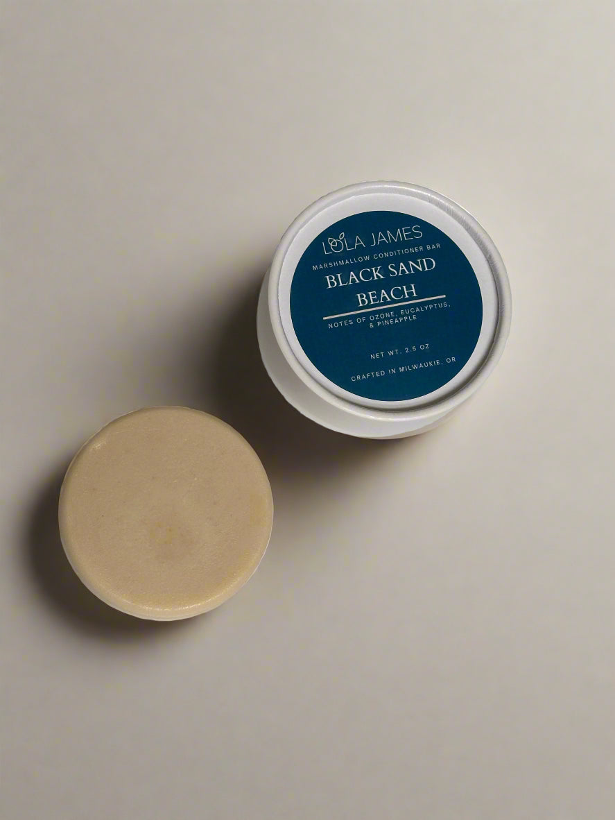 Round Conditioner bar next to blue and white paper tube packaging. Neutral background.