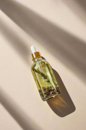Lola James body oil with sprig of lavender and amethyst crystals, gold cap on a white background.