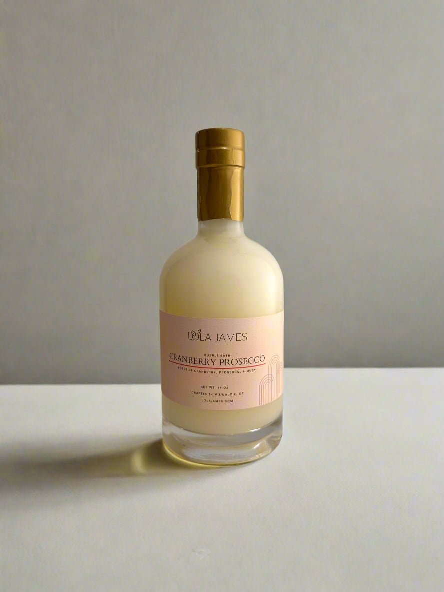 Bottle of Lola James Cranberry Prosecco Bubble Bath on a beige background