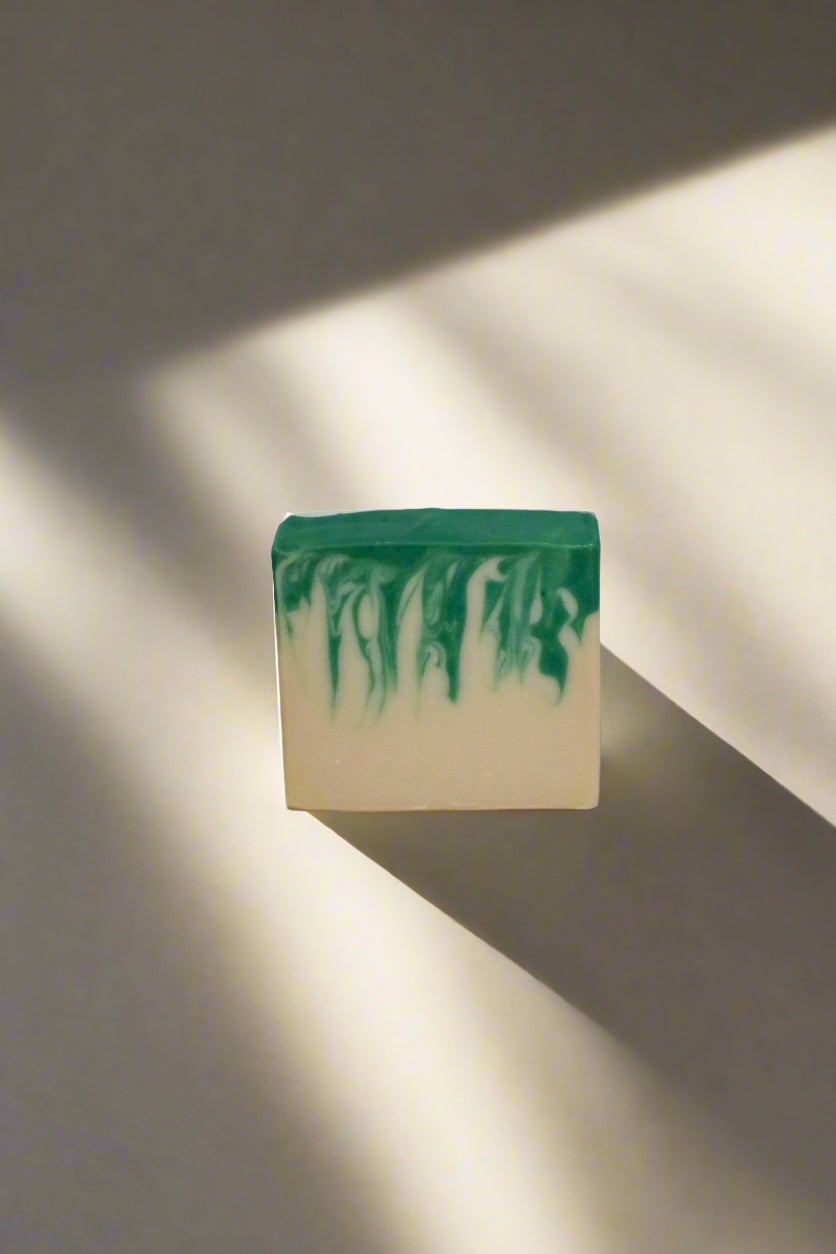 Bar of soap with green and white gradient on a beige background