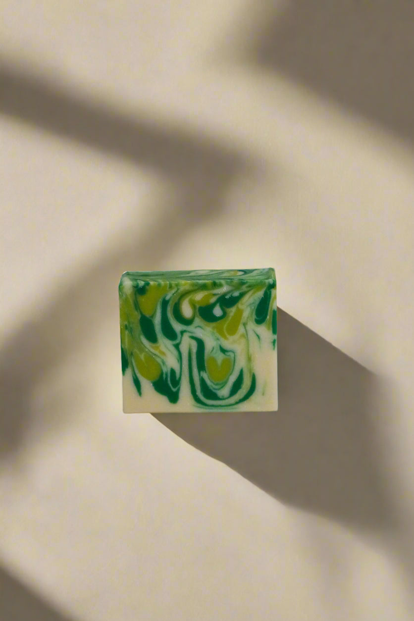 Green and white marbled soap bar on a neutral background